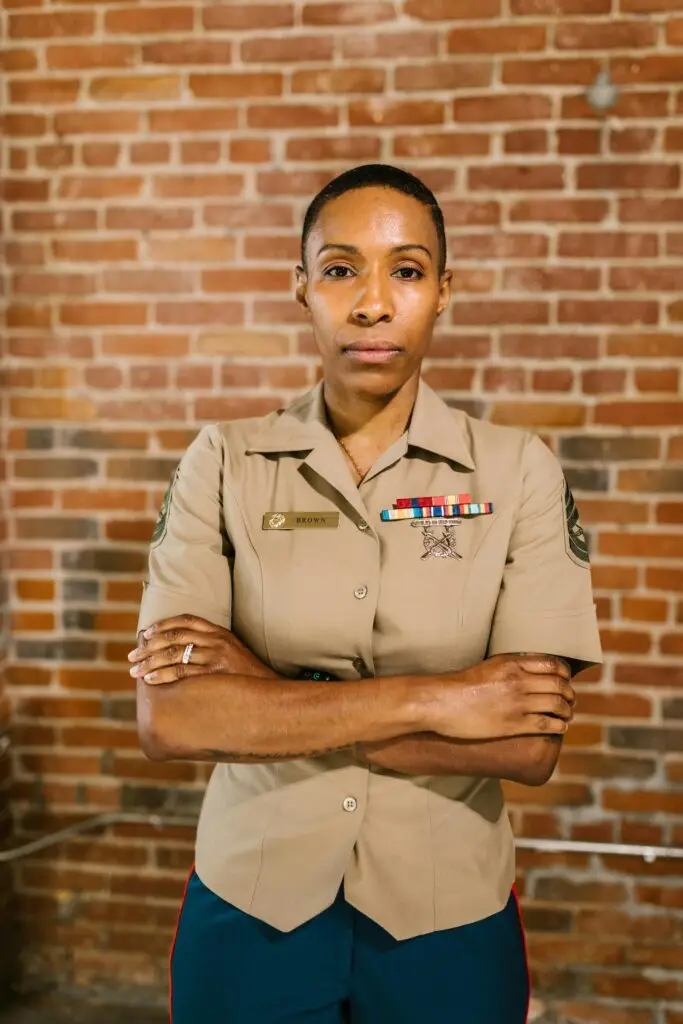 Portrait of a female veteran standing confidently against a brick wall.